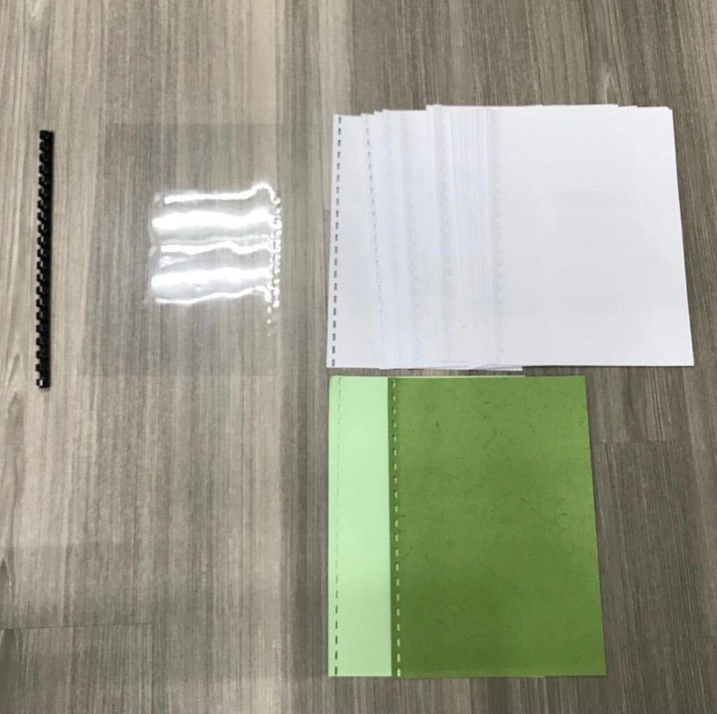 Book binder components sorted into paper, plastic spine, and transparent cover for proper recycling in Singapore.