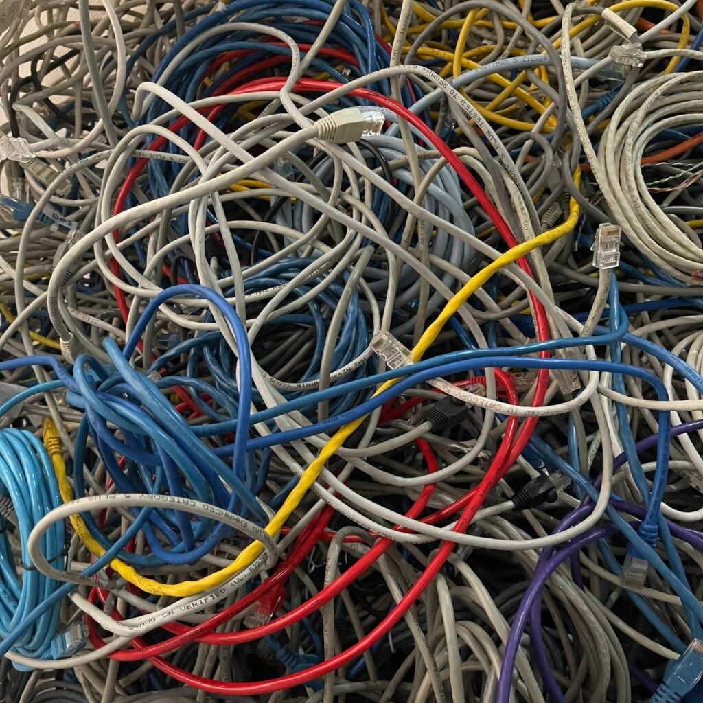 Pile of mixed telecommunication data cables including Cat5 and Cat6 ethernet wires collected for recycling in Singapore.